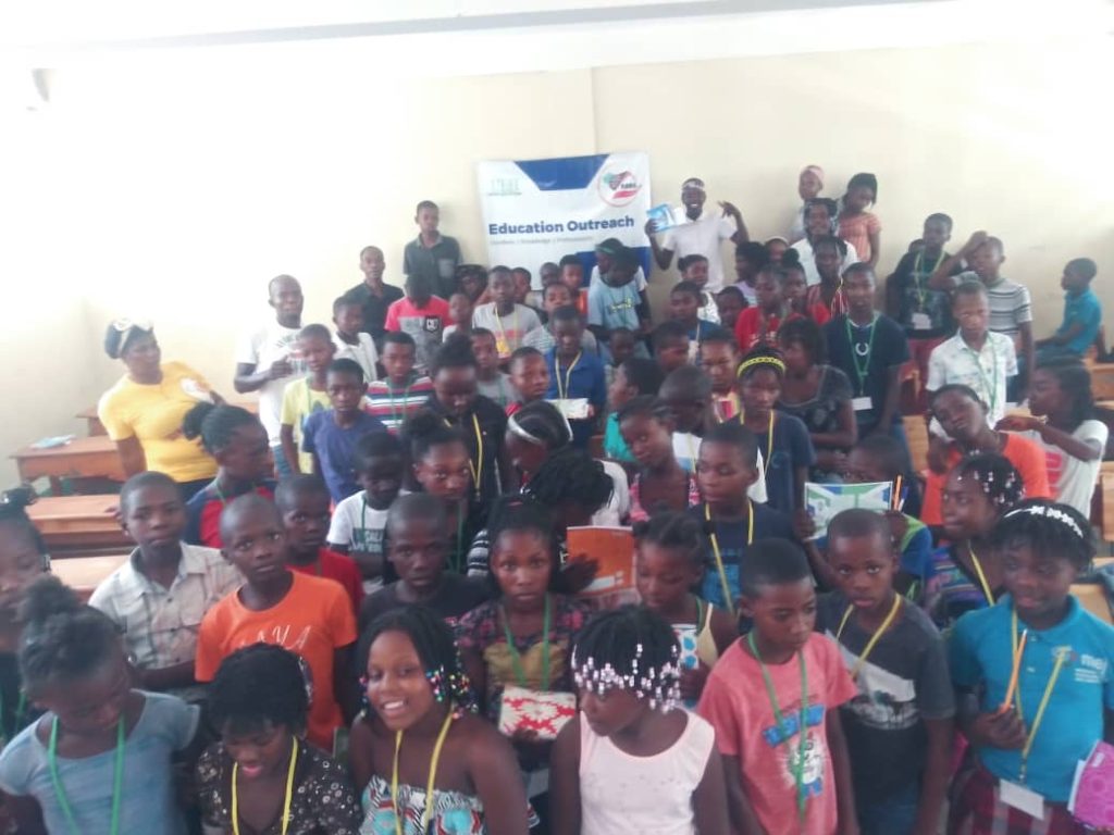 Students gathered indoors with an education outreach banner