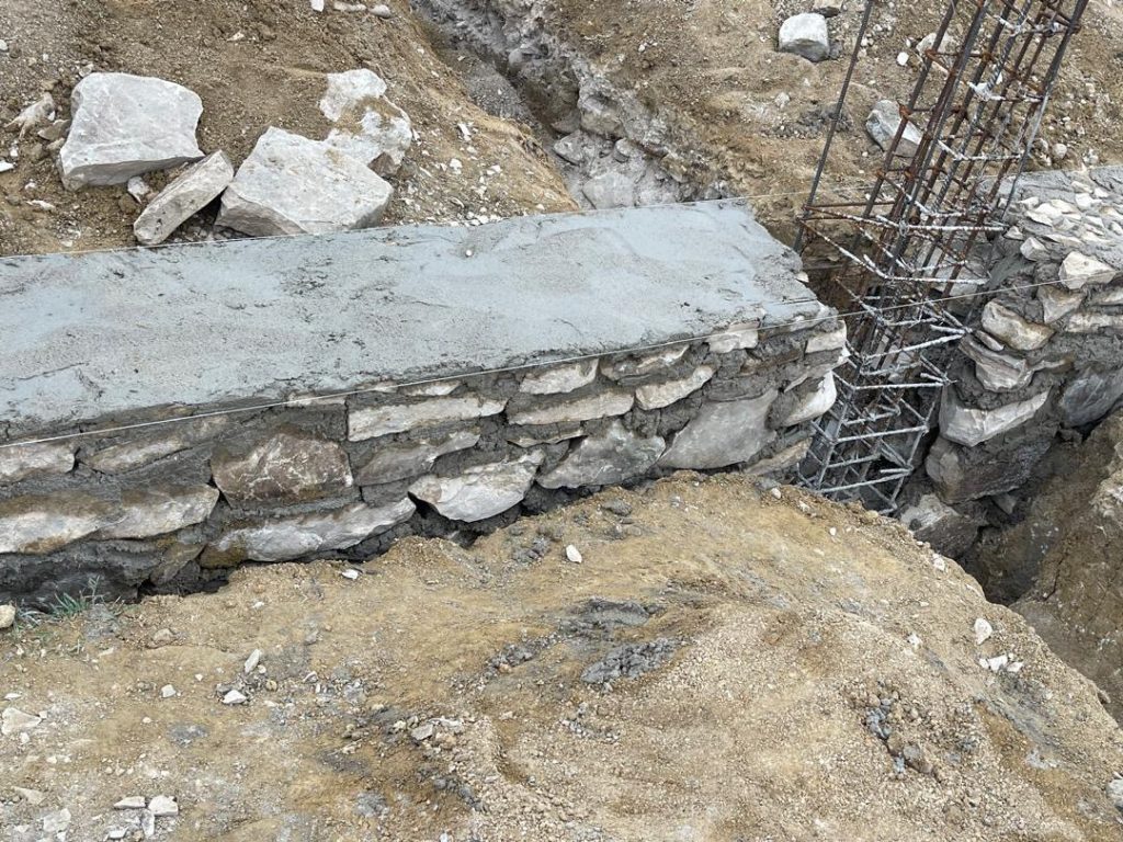 Detail of stone masonry beside a reinforced column cage